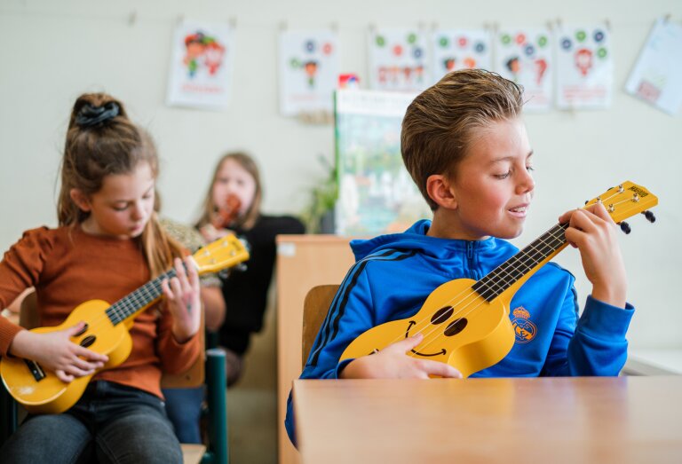 Kinderen genieten van muziekles op de ukulele.